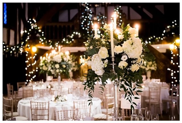 tall candlelit candelabra centrepieces at Great Fosters, white winter wedding flowers