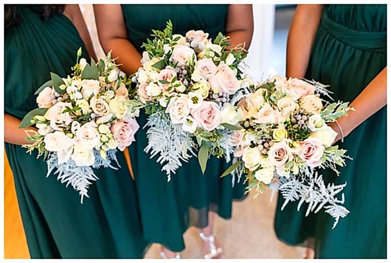 bridesmaids wearing deep green dresses, with bridesmaids bouquets of ivory and blush pink roses and winter ferns